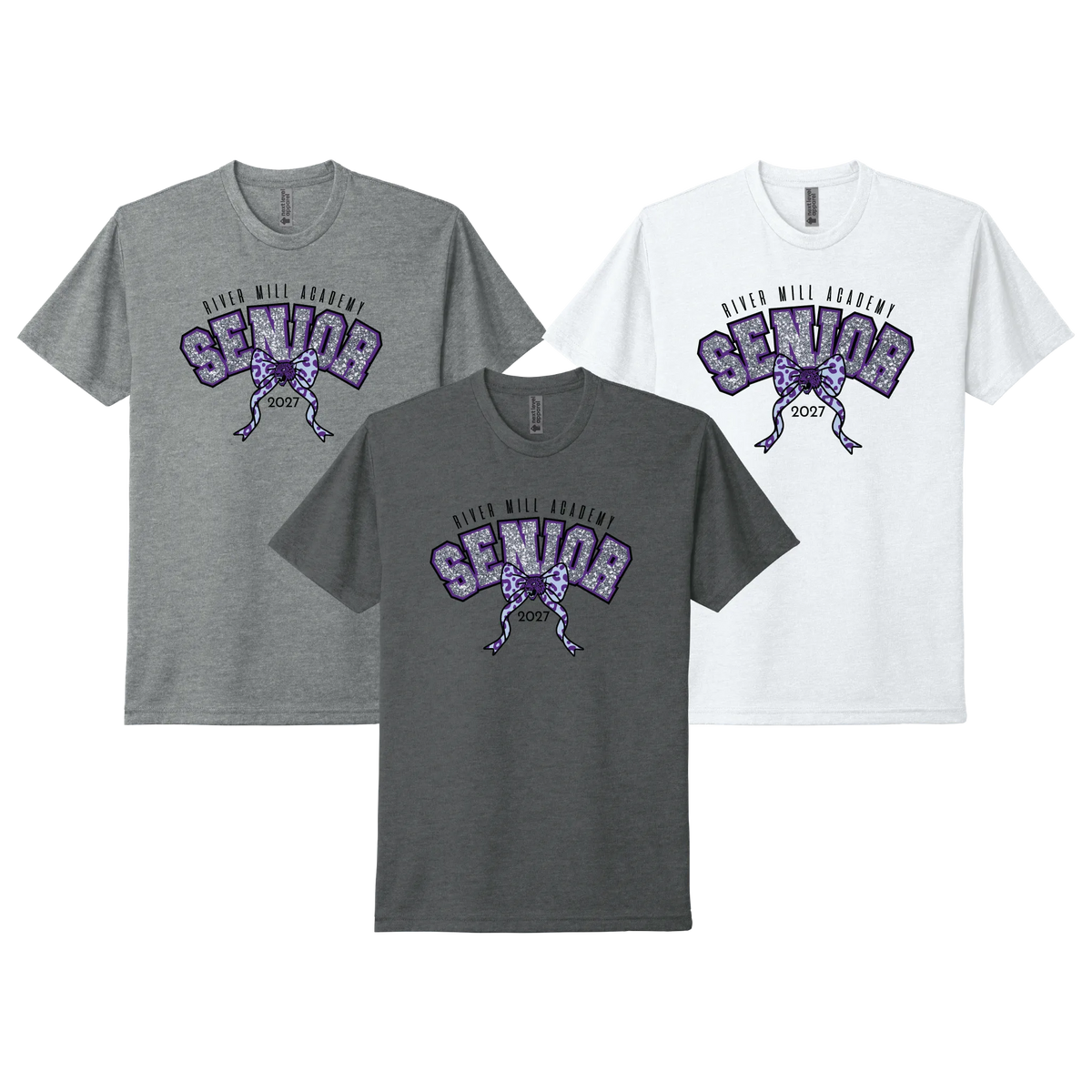 Three short-sleeve crewneck t-shirts shown on a white background: one heather gray, one dark charcoal gray, and one white. Each shirt features a purple and black graphic with the words 'RIVER MALL ACADEMY SENIOR' and a bow with Jaguar mascot in the center knot.